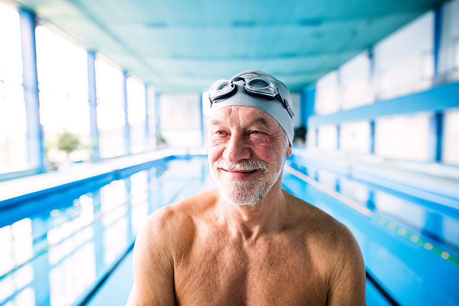 Senior man in an indoor swimming pool. Active pensioner enjoying sport.